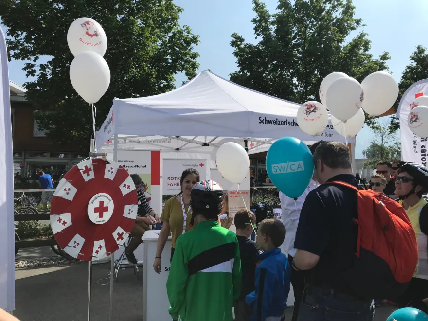 Menschen stehen am Rotkreuz-Stand an um am Glücksrad zu spielen
